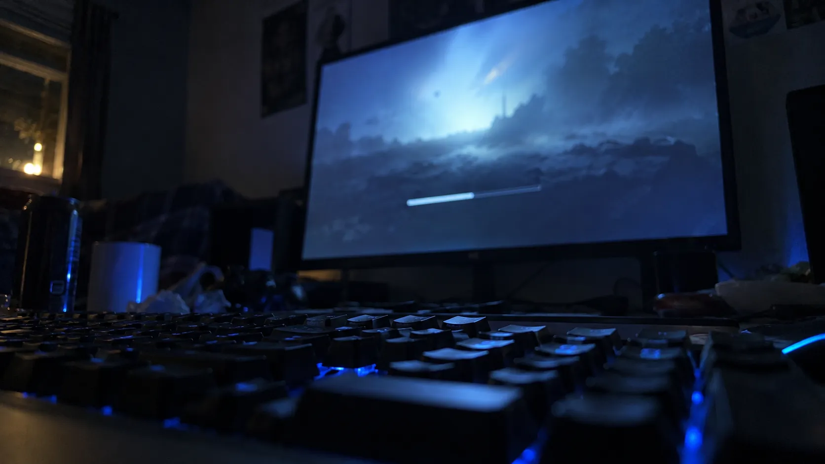 A gaming monitor in a dark room showing a blurred loading screen with a thin progress bar
